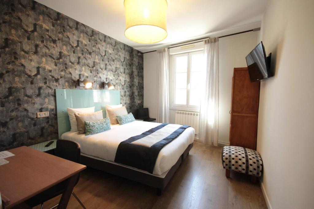 蒙彼利埃Hôtel Des Arts, Artisanal et Indépendant的一间卧室配有一张床、一张桌子和一台电视