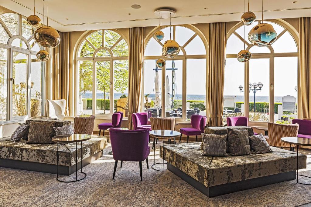 赛巴特班森SEETELHOTEL Strandhotel Atlantic的大堂设有紫色椅子、桌子和窗户