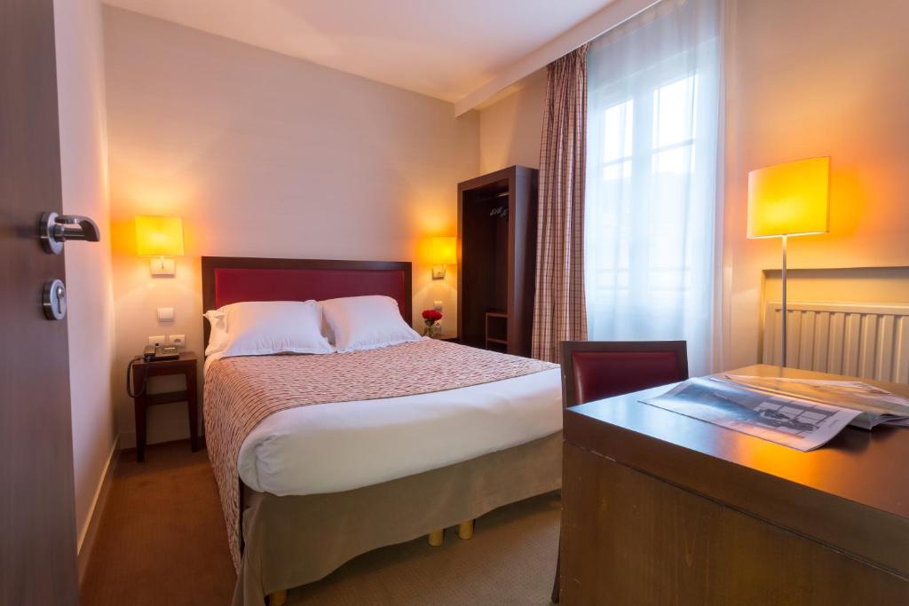 万塞讷乐居酒店的配有一张床、一张书桌和一扇窗户的酒店客房