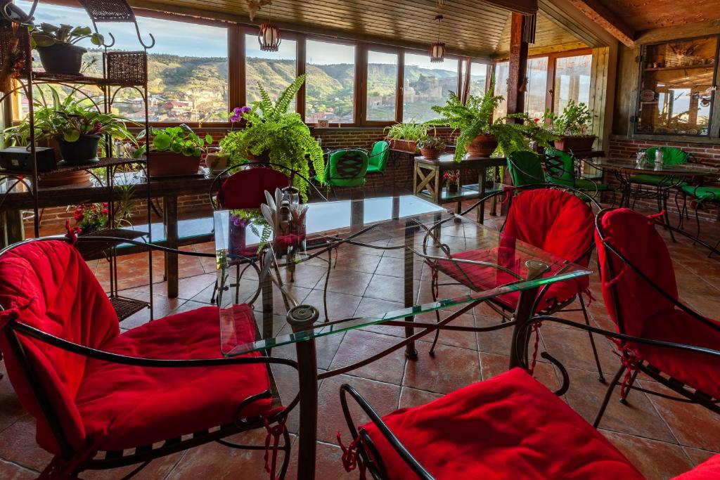 第比利斯阁楼酒店的一间设有红色椅子和桌子及窗户的房间