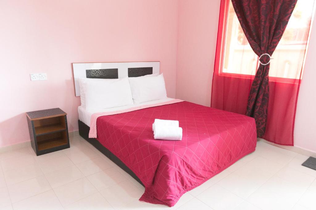 珍南海滩斯里梅洛尔汽车旅馆的一间卧室配有一张带红色毯子的床和窗户。