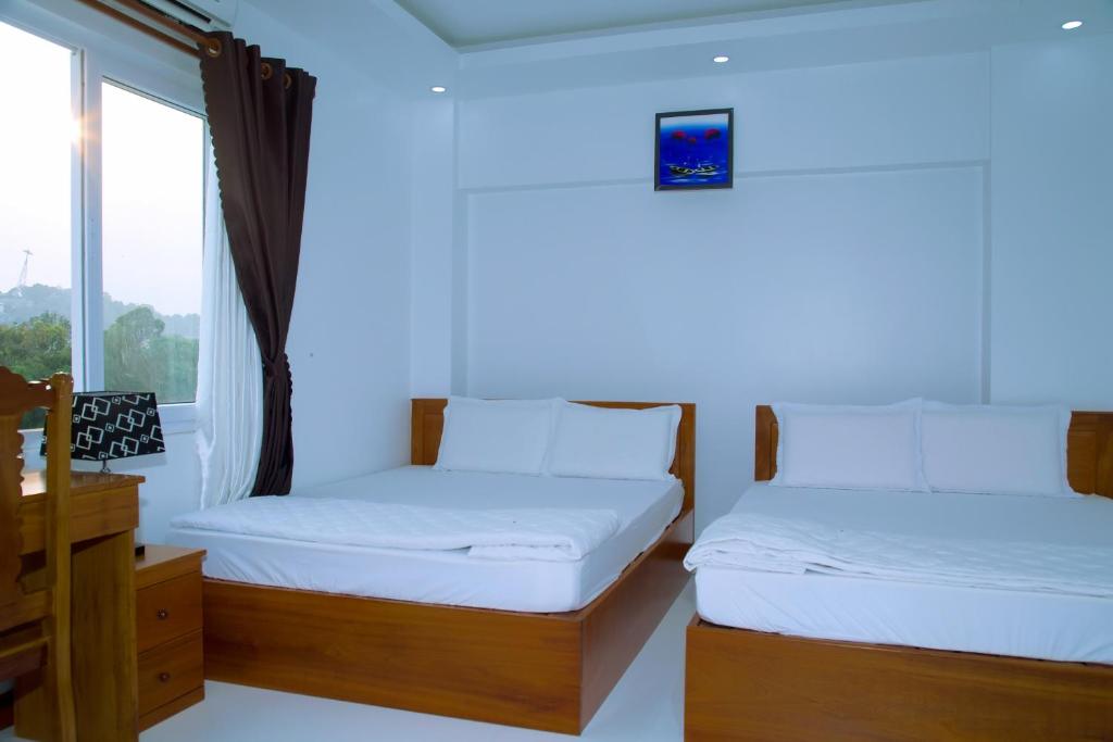 朱笃Hotel Đăng Khôi Núi Sam的带窗户的客房内的两张床