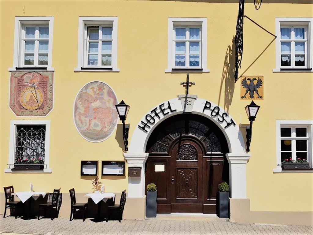 WeißenstadtGarni Hotel Post的黄色的建筑,设有木门和桌椅
