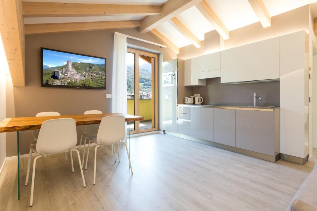 德利纳La Giostra Home Apartments的厨房配有白色橱柜和木桌及椅子