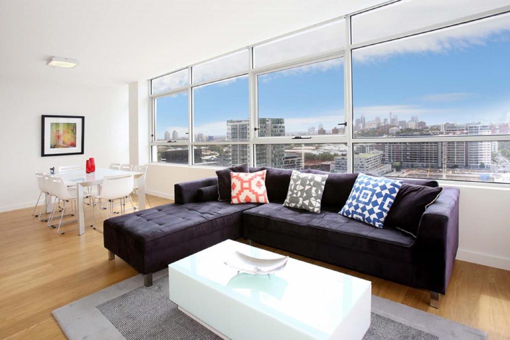 悉尼G1708S三卧室泽特蓝公寓的客厅配有黑色沙发和桌子