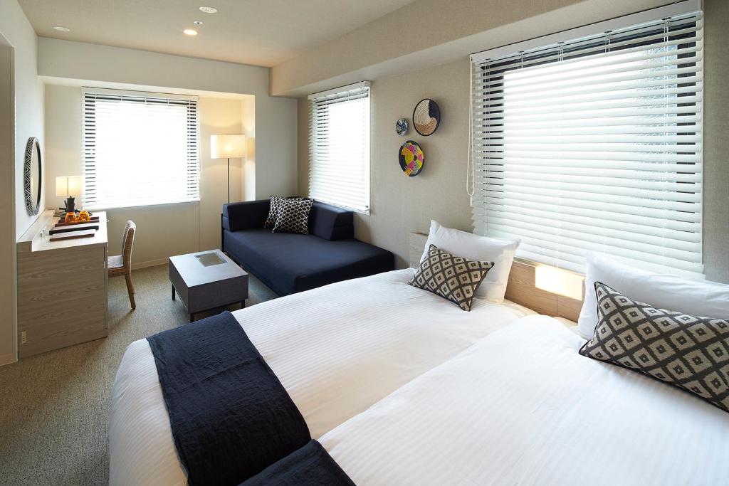 大阪DEL style Osaka Higashi Temma by Daiwa Roynet Hotel的一间卧室配有一张床、一把椅子和一张沙发