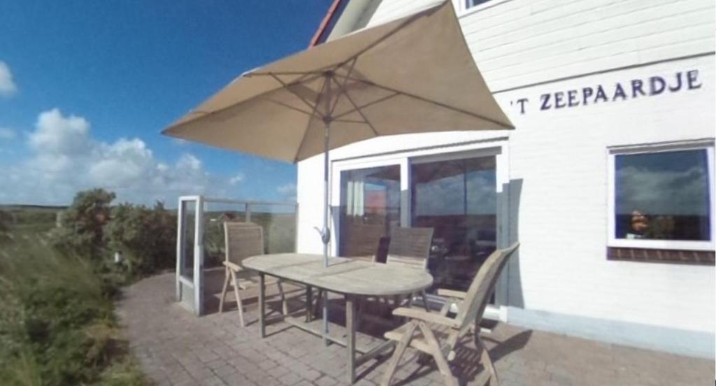 Midsland aan Zee't Zeepaardje的庭院内桌椅和遮阳伞