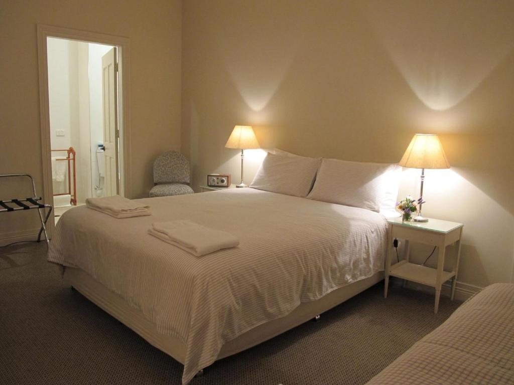 BarrabaThe Playhouse Hotel的一间卧室配有一张带两盏灯的大型白色床。