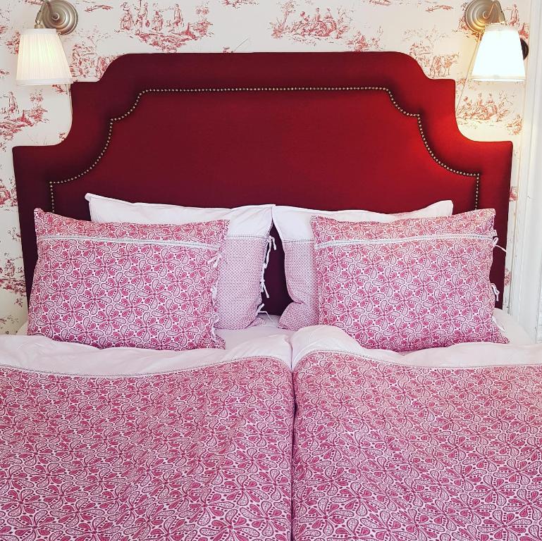 韦斯特罗斯Hem till Gården boutique hotel的床上配有粉色和白色枕头的床