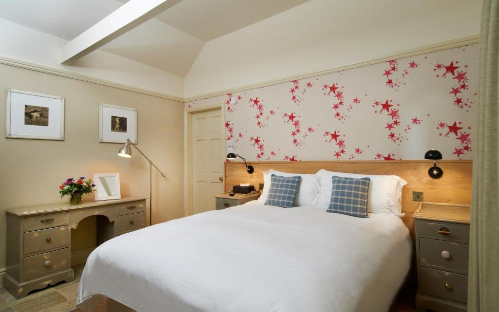 Farnham博物馆旅馆的卧室配有一张白色大床,墙上挂着红色鲜花
