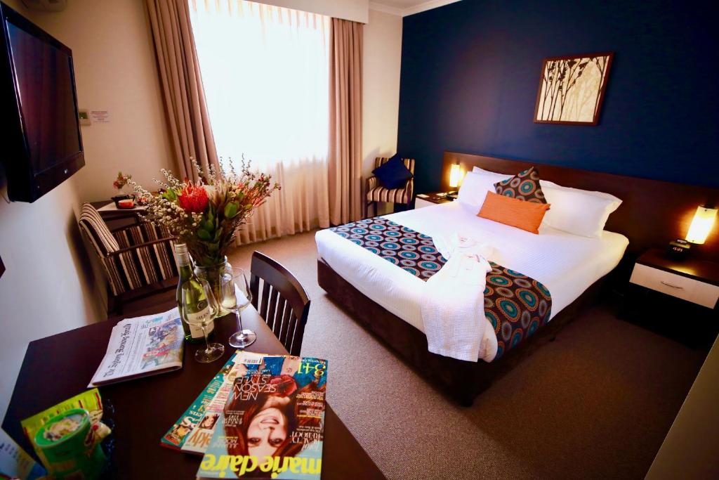 悉尼175 Hotel Westmead的酒店客房设有两张床和一张桌子,配有一张桌子