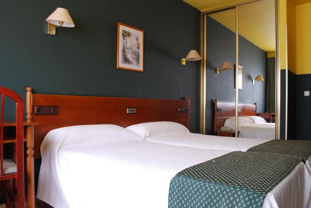 圣地亚哥－德孔波斯特拉圣雅各布酒店的一间卧室配有两张床和镜子