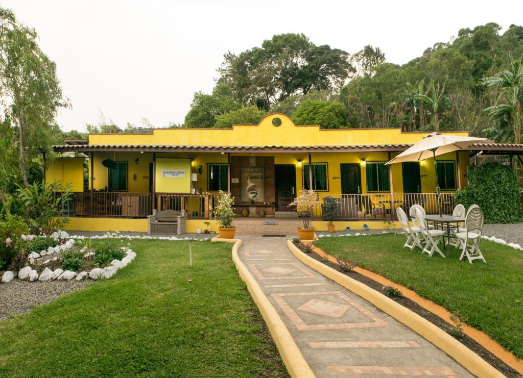 下博克特Agaseke Lodge Boquete的院子里的黄色房子,配有桌椅