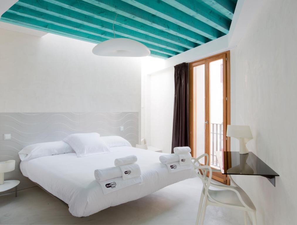 托莱多Antidoto Rooms San Agustín - Recomendado para adultos的卧室配有白色的床和蓝色的天花板