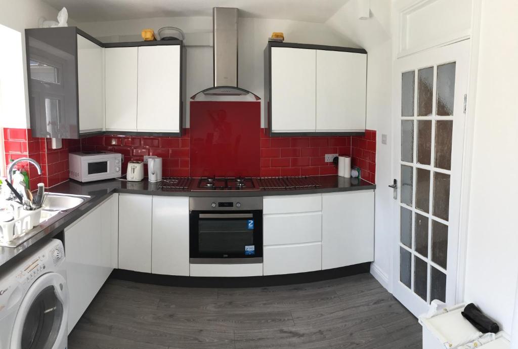 亨顿Rushden Vacation Home的厨房配有白色橱柜和红砖墙