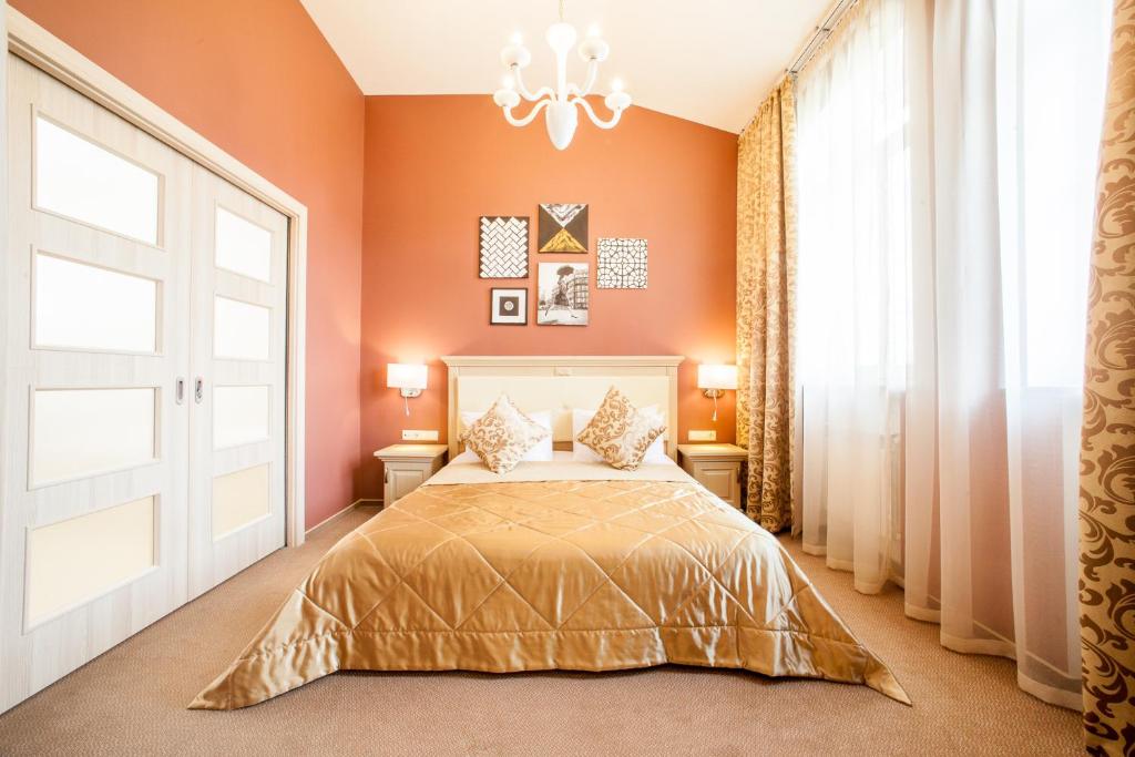 基辅麦金托什酒店的一间卧室配有一张带橙色墙壁和吊灯的床。