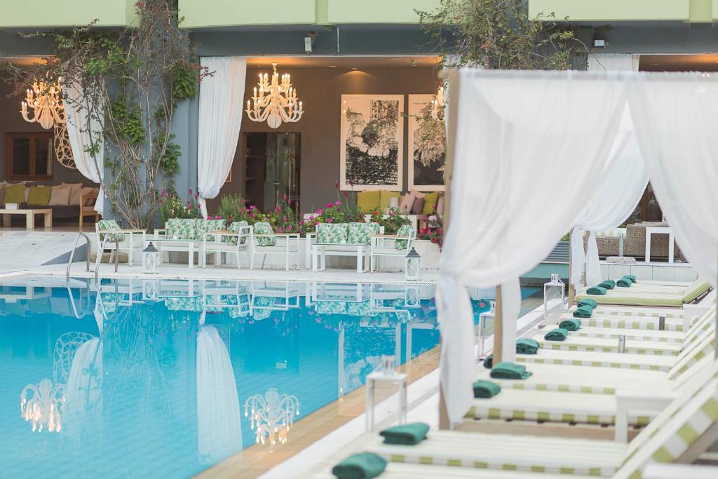 斯基亚索斯镇游泳池艺术酒店，菲莲酒店及度假村的游泳池畔的一张带白色椅子的桌子