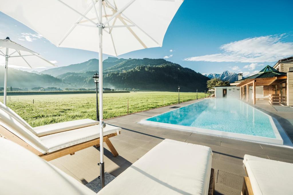 齐勒河谷采尔特里萨健康-美食-酒店的一个带遮阳伞和椅子的游泳池