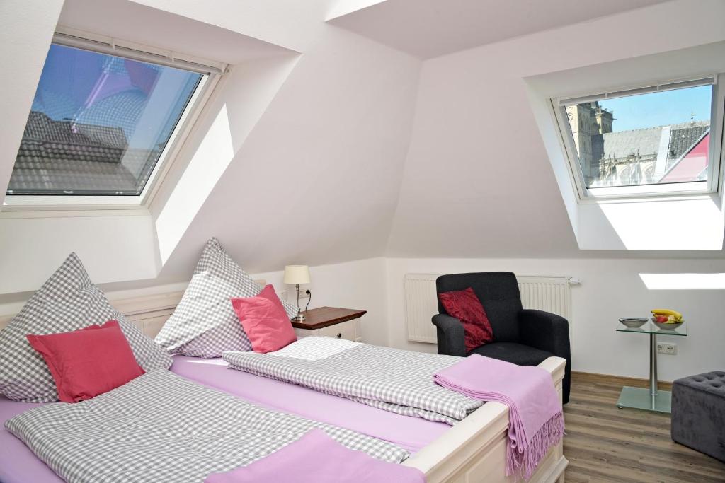 克桑滕Weindepot Xanten的一间卧室配有一张床和一把椅子,还有两个窗户