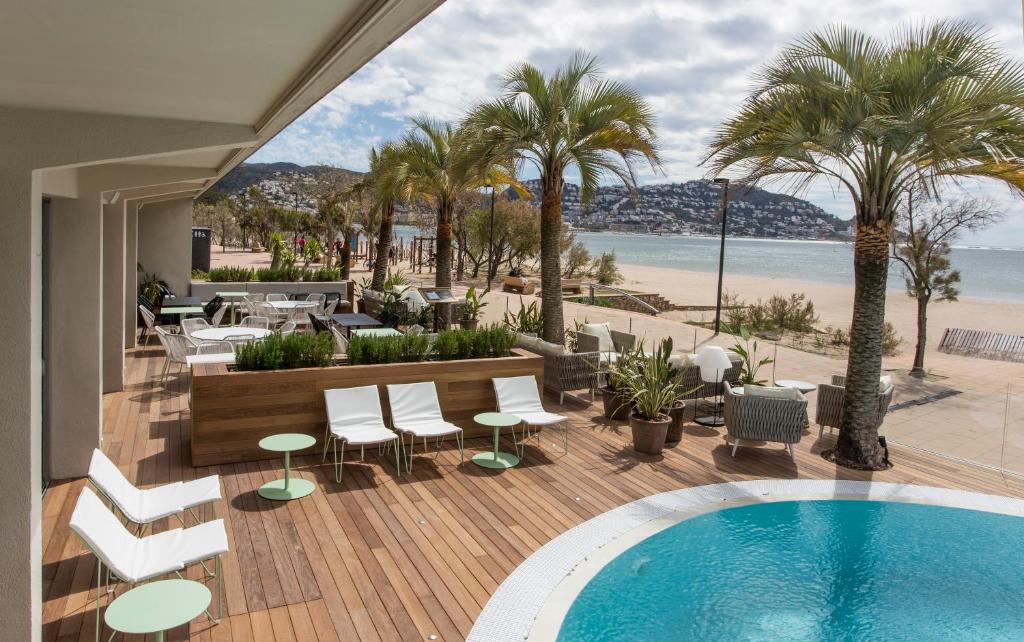 罗萨斯Hotel Maritim的棕榈树和海滩甲板上的游泳池