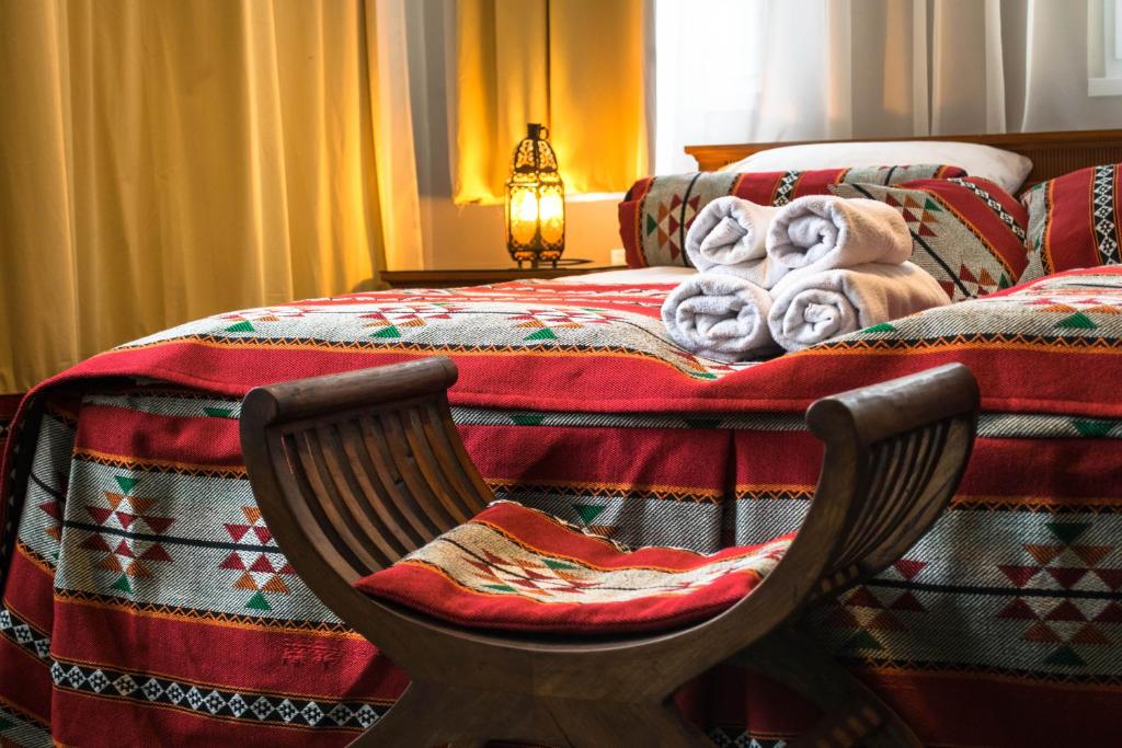 尼赖吉哈佐Petra Hotel的一间卧室配有一张带毯子和椅子的床