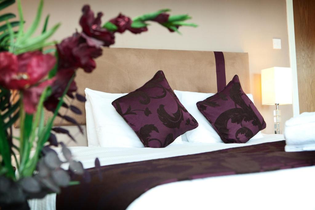 格拉斯哥The Spires Serviced Apartments Glasgow的一间卧室配有一张带紫色和白色枕头的床