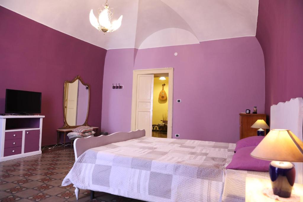 卡塔尼亚la locanda del centro storico的紫色卧室配有一张床和镜子