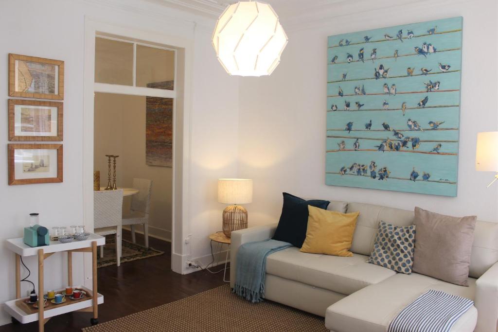 里斯本Bird's Nest Lisbon Apartment的客厅配有沙发和墙上的绘画
