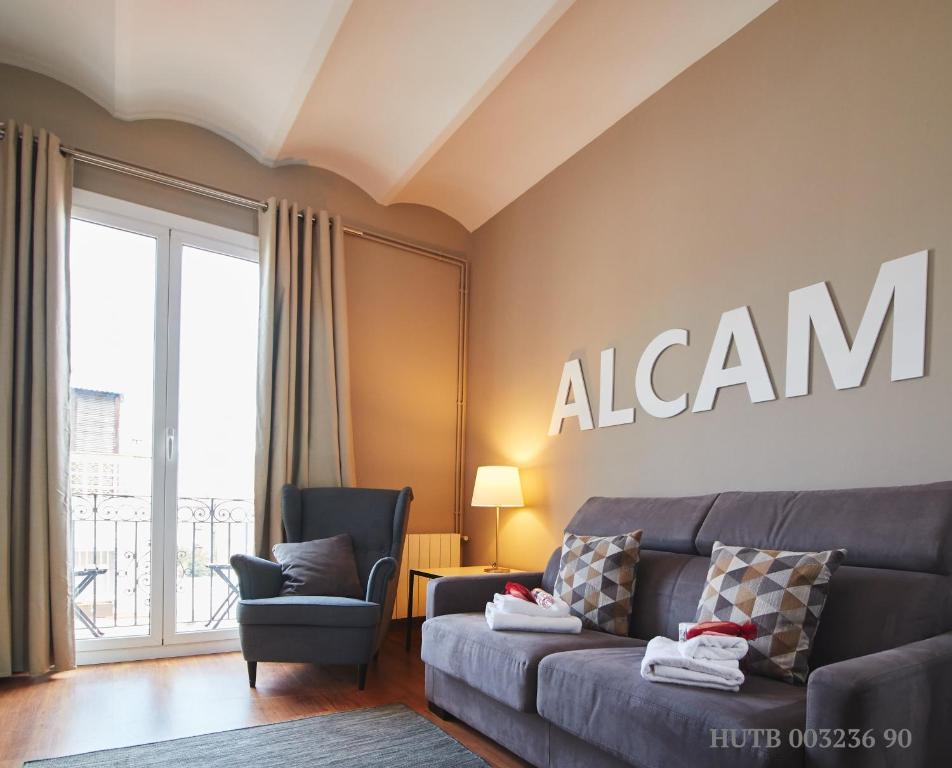巴塞罗那阿尔卡姆黎扎公寓的客厅配有沙发和墙上的标志