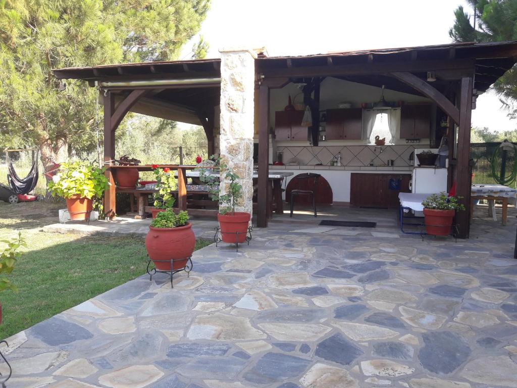 奥马斯帕纳吉亚斯Konaki Guesthouse的石头庭院,设有种植了盆栽植物的凉亭