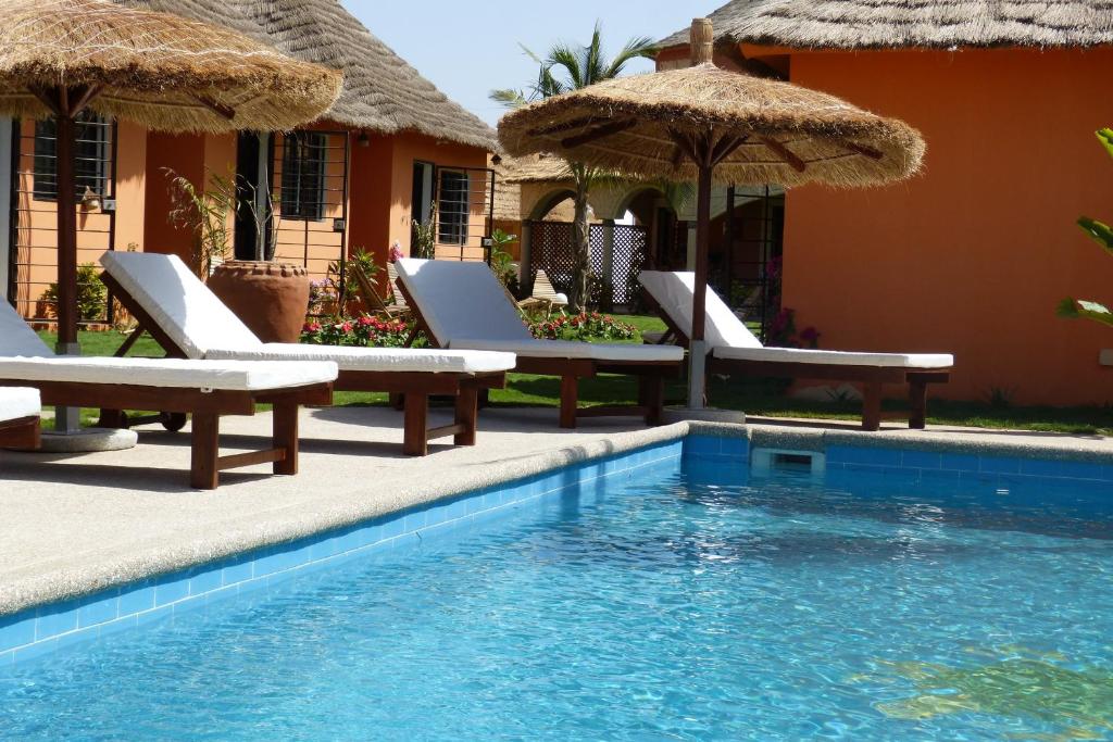 姆布尔Terra Lodge Sénégal的一个带椅子和遮阳伞的游泳池的度假酒店