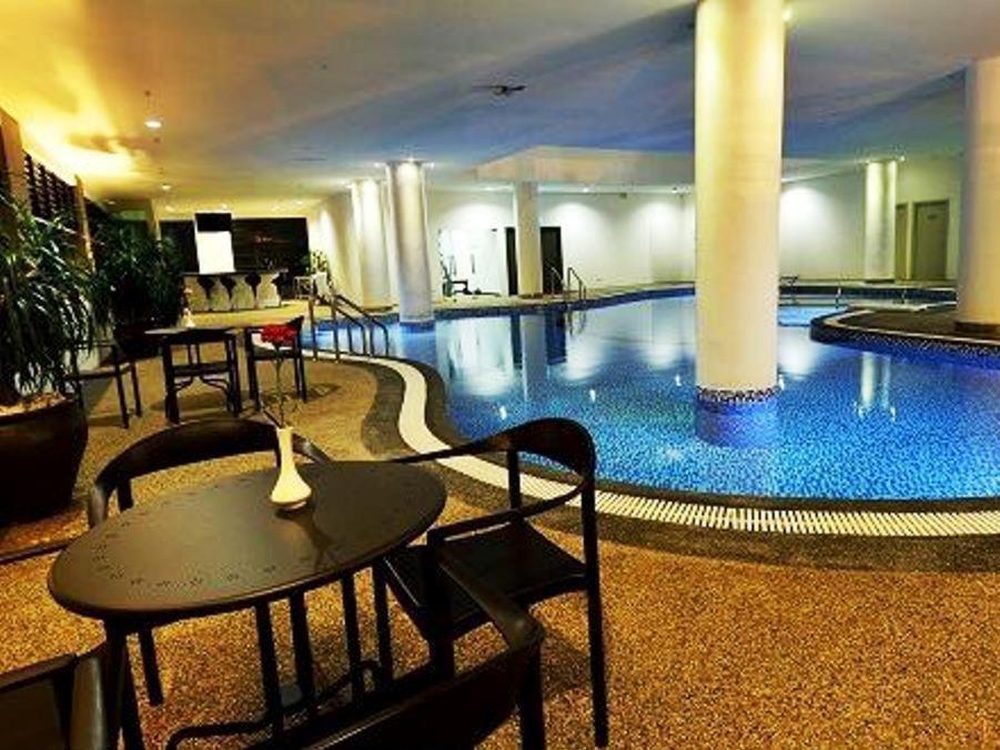 哥打巴鲁哥打巴鲁假日别墅套房酒店的一个带桌子和桌子的大型游泳池