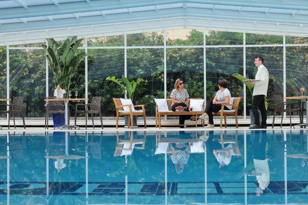 加利波利Joli Park Hotel - Caroli Hotels的站在游泳池前的人,有人坐在游泳池前