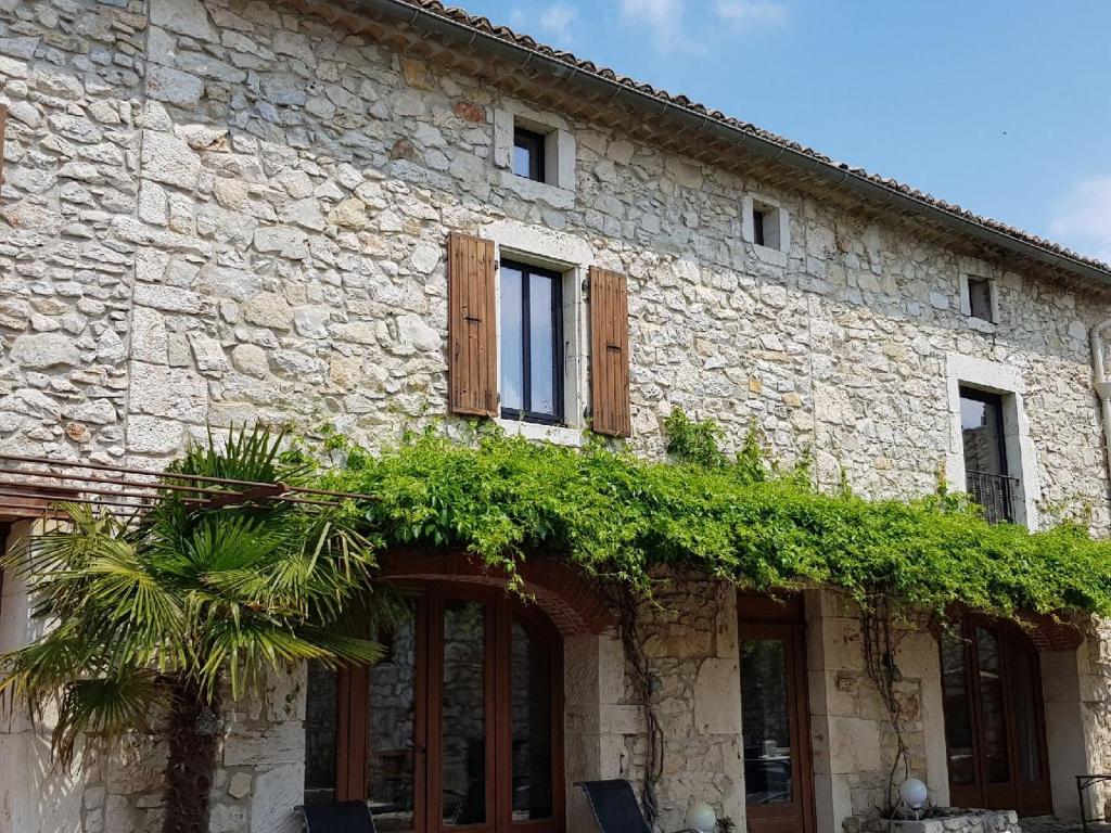 Saint-RemèzeLa bastide Maë的一座石头建筑,里面装有窗户和植物