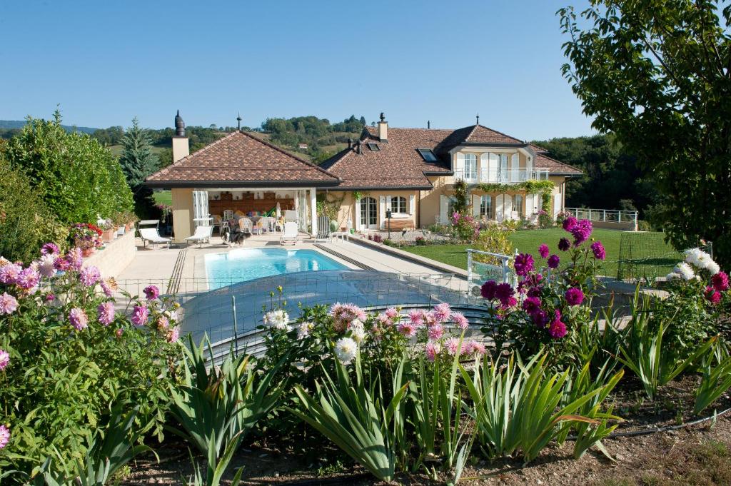 Genolier乐利尔家庭旅馆的一座带游泳池和鲜花的房子
