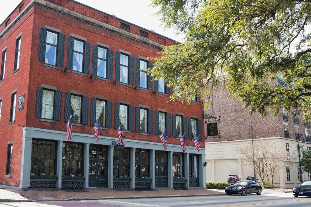 萨凡纳East Bay Inn, Historic Inns of Savannah Collection的前面有美国国旗的红砖建筑