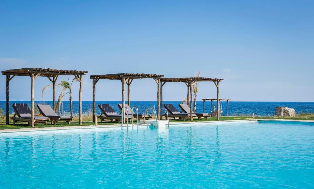 里科索翁Kymata Bohemian Villas的一个带椅子的游泳池,背景是大海