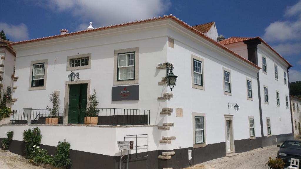 奥比多斯Pousada Vila Óbidos的白色的建筑,设有绿门
