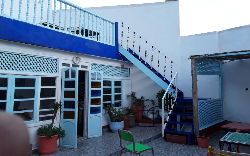 索维拉蓝白旅舍的一座拥有蓝色楼梯和绿色椅子的建筑