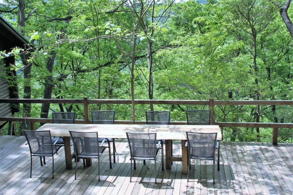 饭能市Shomarutoge Garden House的树木繁茂的甲板上的木桌和椅子
