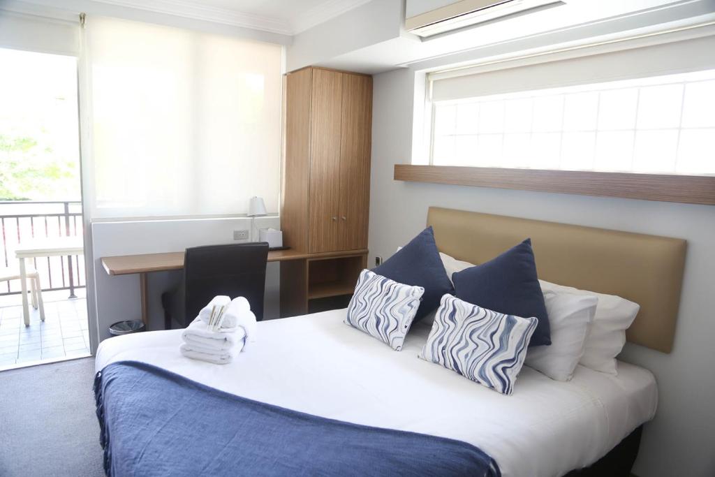悉尼布伦海姆酒店的一间卧室配有一张带蓝色和白色枕头的床