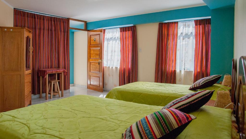 乌鲁班巴B&B Valcava的一间卧室设有两张绿色的床和红色窗帘