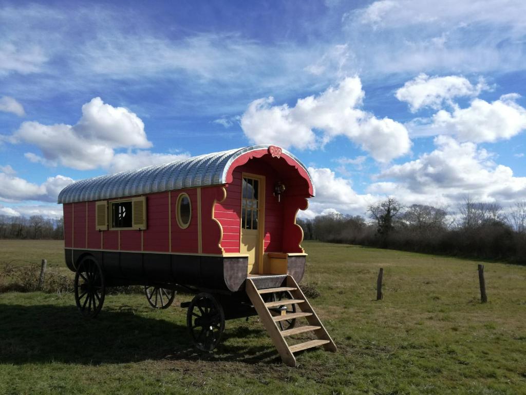 BeaulonLa Roulotte des Grillots的一辆红色的火车车停在田野里