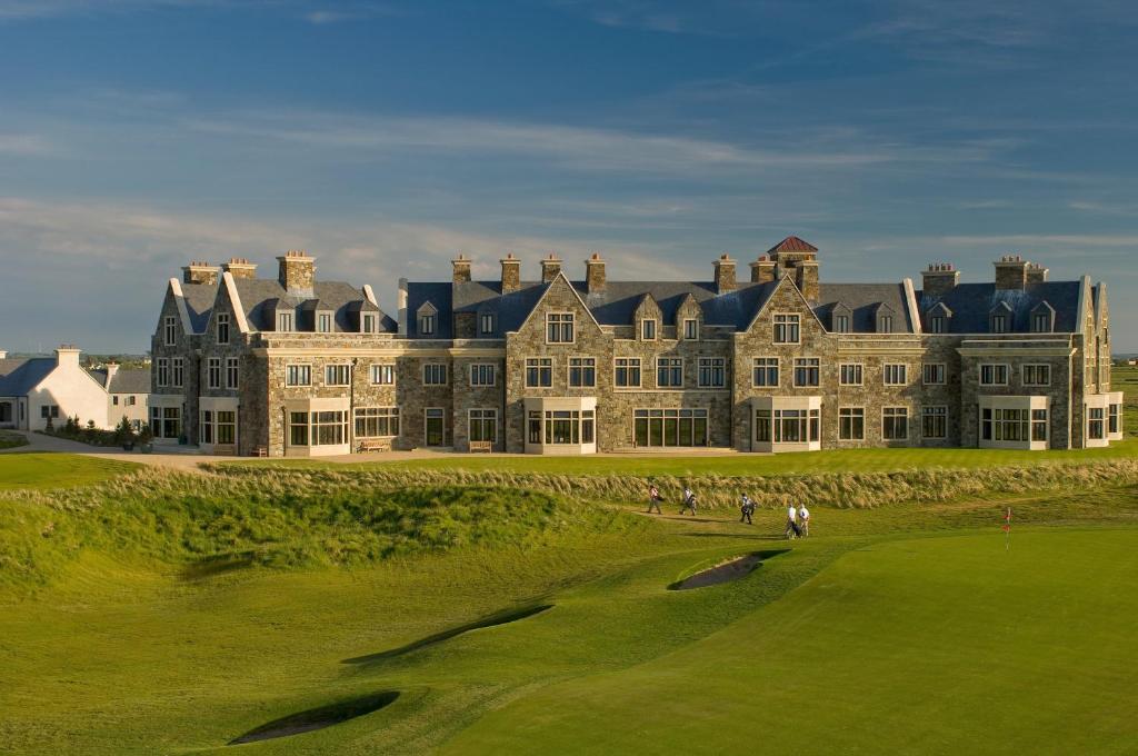 敦贝格Trump International Golf Links & Hotel Doonbeg Ireland的一座大型建筑,在高尔夫球场上有人
