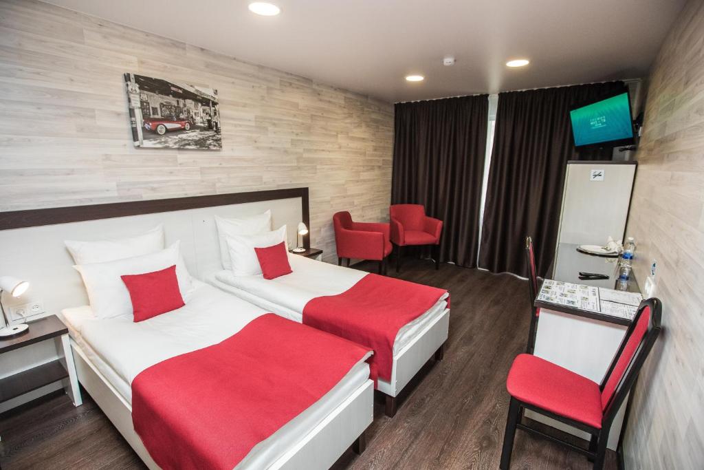 巴尔瑙尔福克斯城市酒店的酒店客房,设有两张床和红色椅子