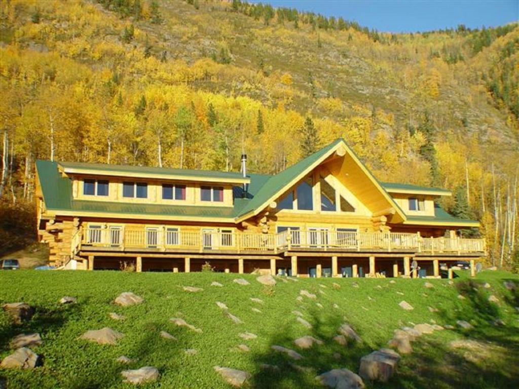 Hudson Hope威利斯顿湖度假酒店的一座大型黄色房屋,设有绿色屋顶