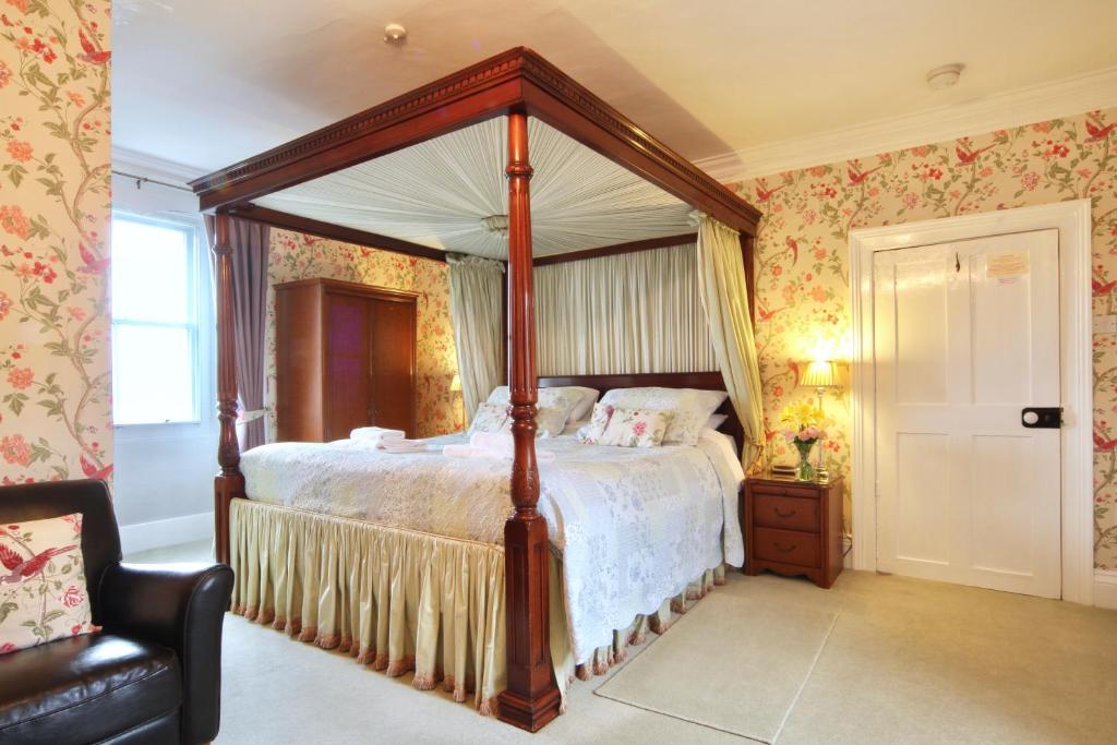莱伯恩老牧师之家酒店的一间卧室配有一张天蓬床和一把椅子