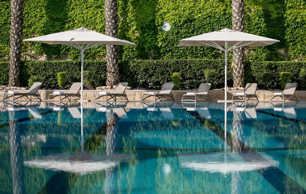 耶路撒冷耶胡达酒店 的一个带椅子和遮阳伞的游泳池