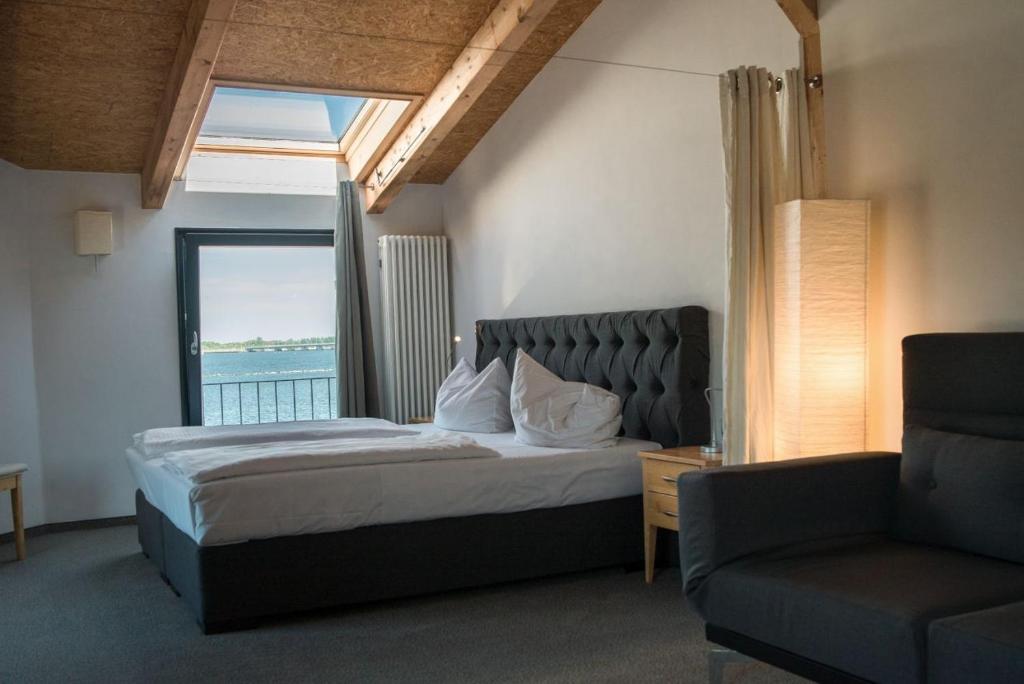施特拉尔松德Hotel Alter Hafenspeicher的卧室配有床、椅子和窗户。