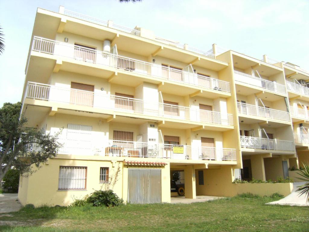 莱斯卡拉Apartamentos Riells de Mar的一座大型黄色建筑,设有白色阳台